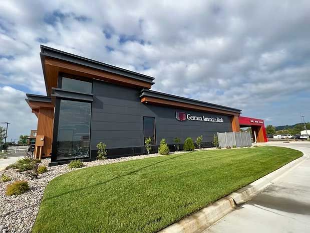 Exterior of a dark gray building with wooden accents and the sign 