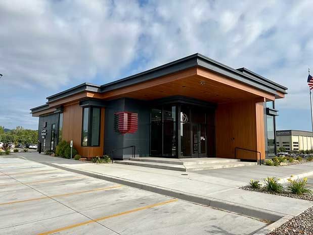 Modern building with brown and dark gray facade, large windows, and a flag.