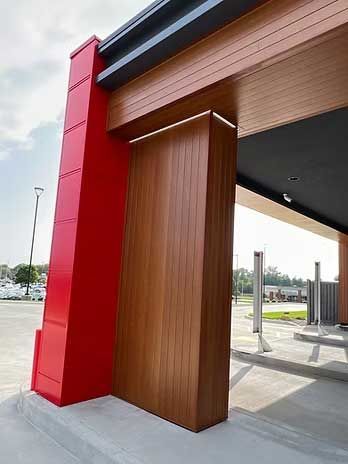 Red and brown exterior architectural detail of a building entrance with a drive-thru lane.