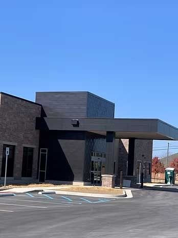 Modern brick building with black accents and canopy, blue sky.