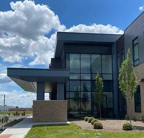 Modern building with large glass windows, blue and tan accents, under a cloudy sky.