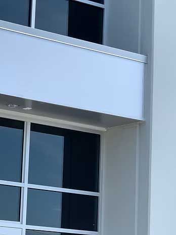 Modern building exterior with white walls, windows, and silver trim.