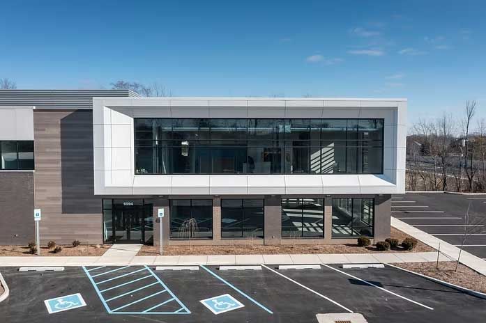Modern two-story building with large windows and an accessible parking space.