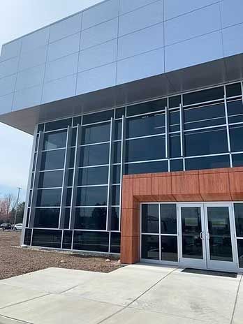Modern building exterior with large windows, silver metal siding, and a brown entrance.