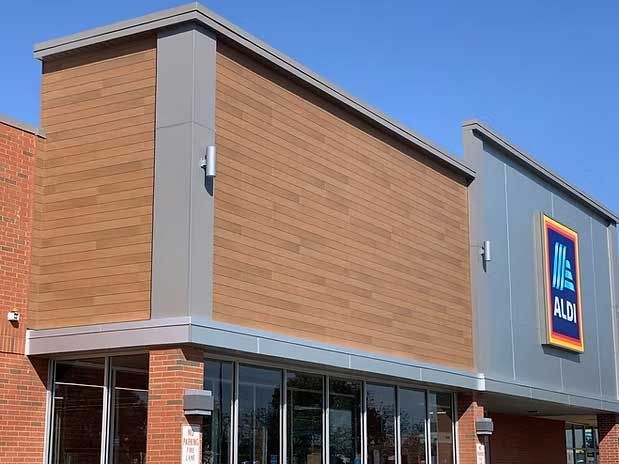 Exterior of an Aldi grocery store with wood-look siding, gray accents, and blue logo.