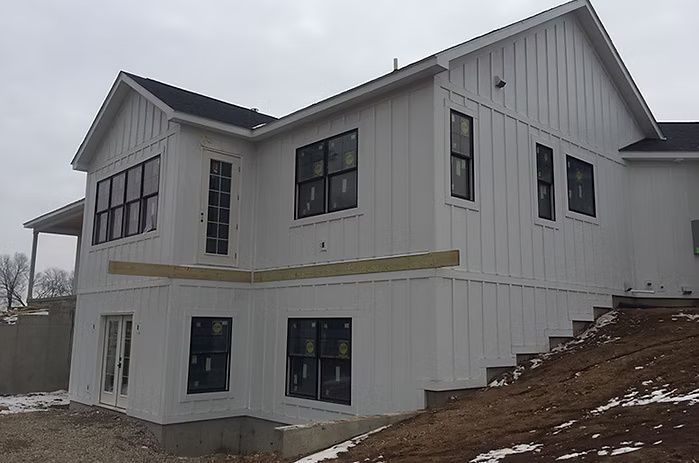White house under construction with black windows and steps.