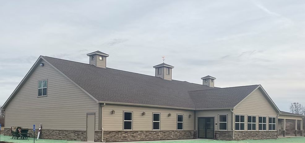 A tan-colored building with a dark roof. It has several small square cupolas and windows.