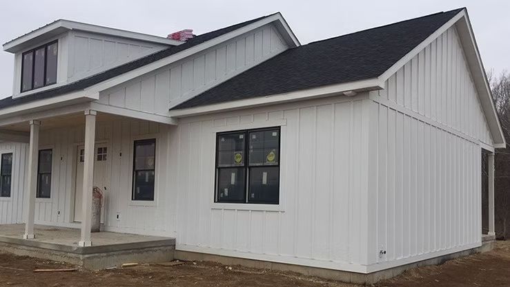 White house under construction with black roof and windows.