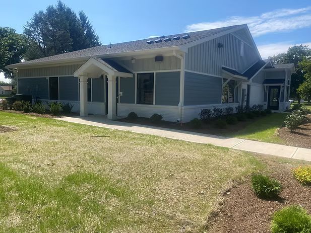 Blue and tan one-story building with a grassy lawn.