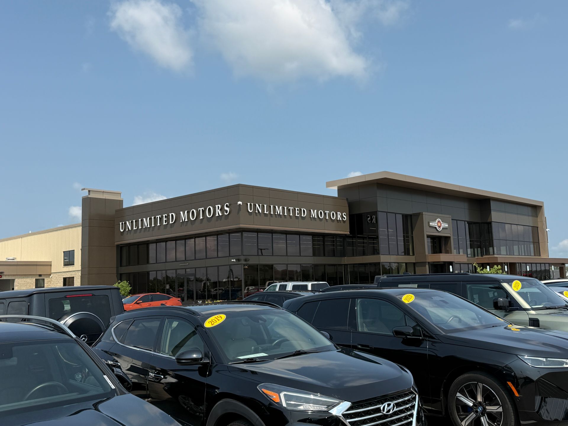 Parking lot outside Desert Hills Premium Outlets with several parked cars under a blue sky.