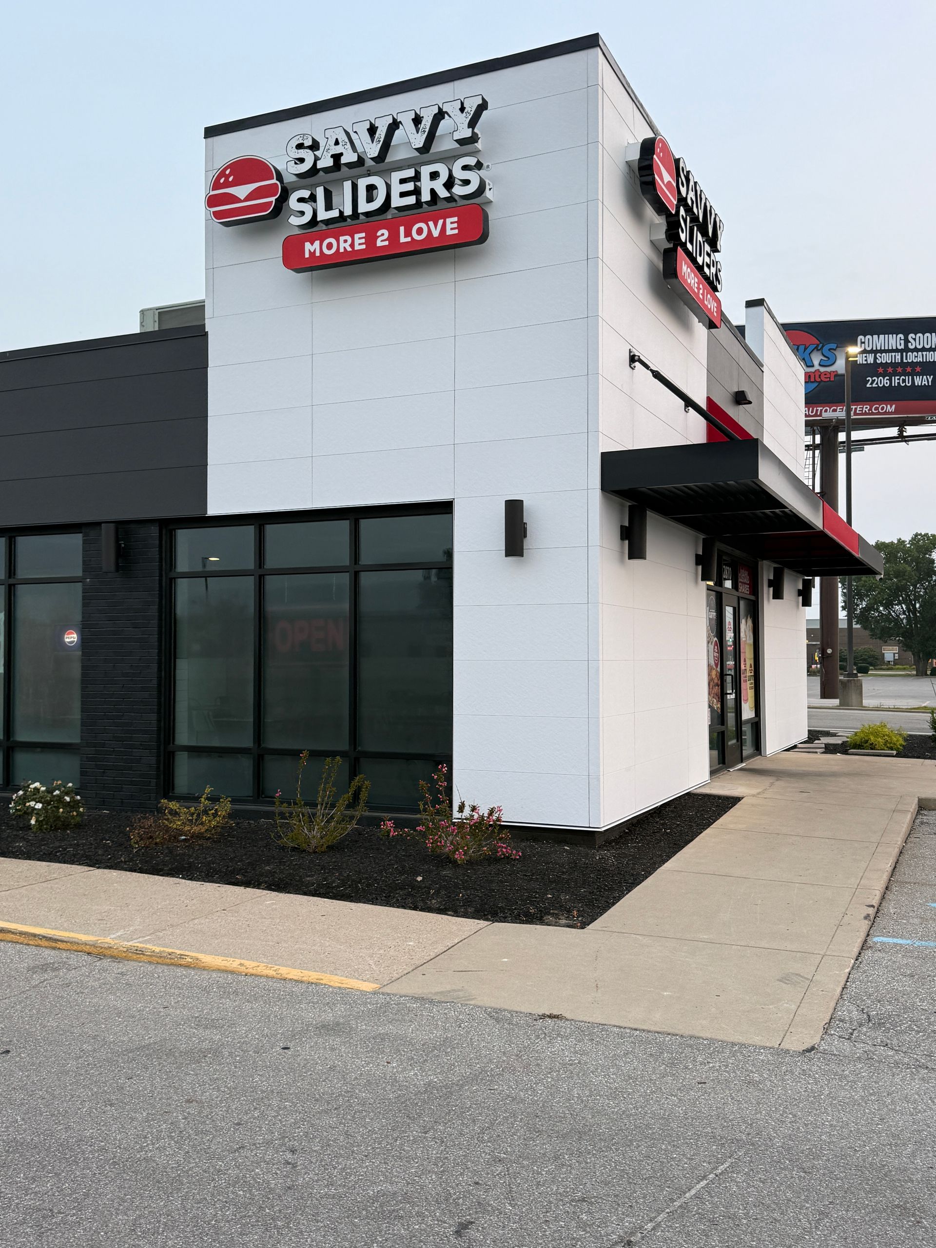 Exterior of a Sliders restaurant with white and black facade and red signage on a sidewalk corner