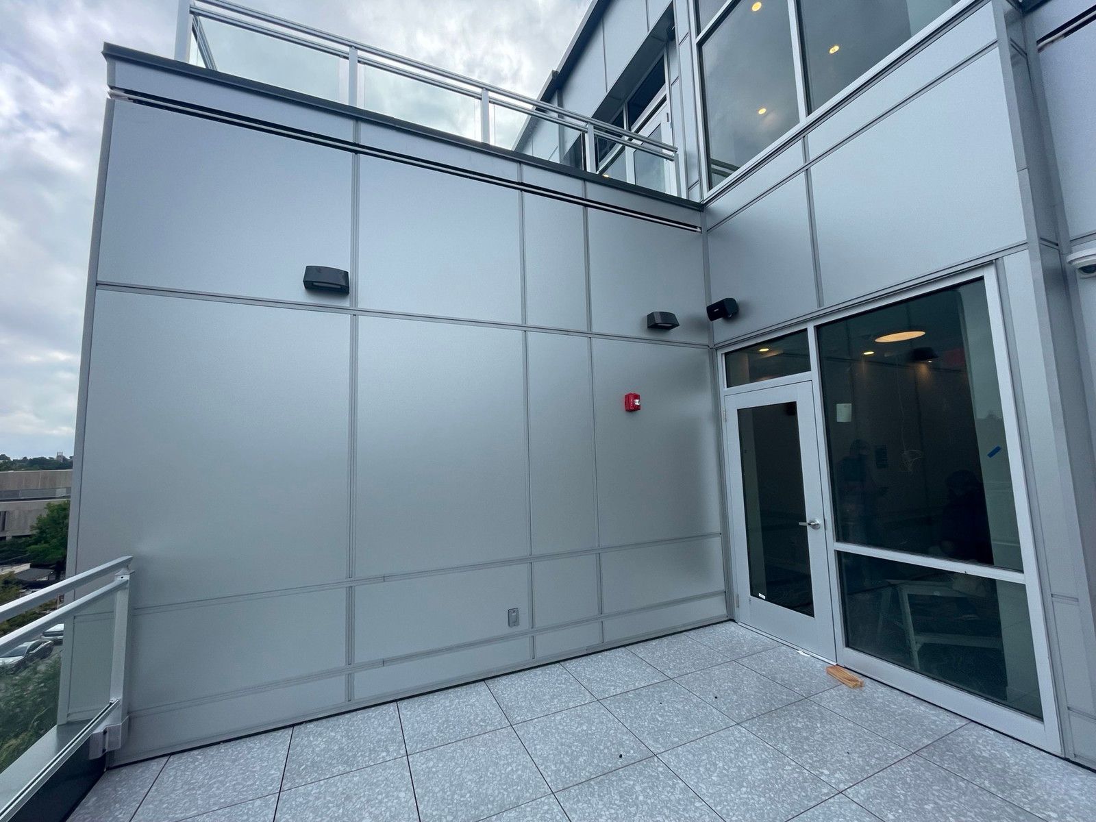 Modern building terrace with gray metal wall panels and a glass door leading inside