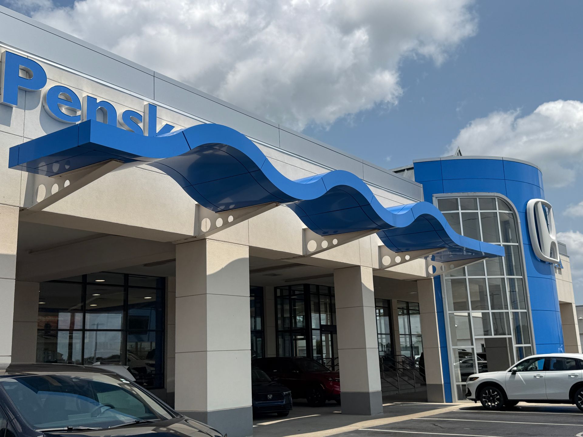 Penske truck rental storefront with blue awning, glass entrance, and parked vehicles