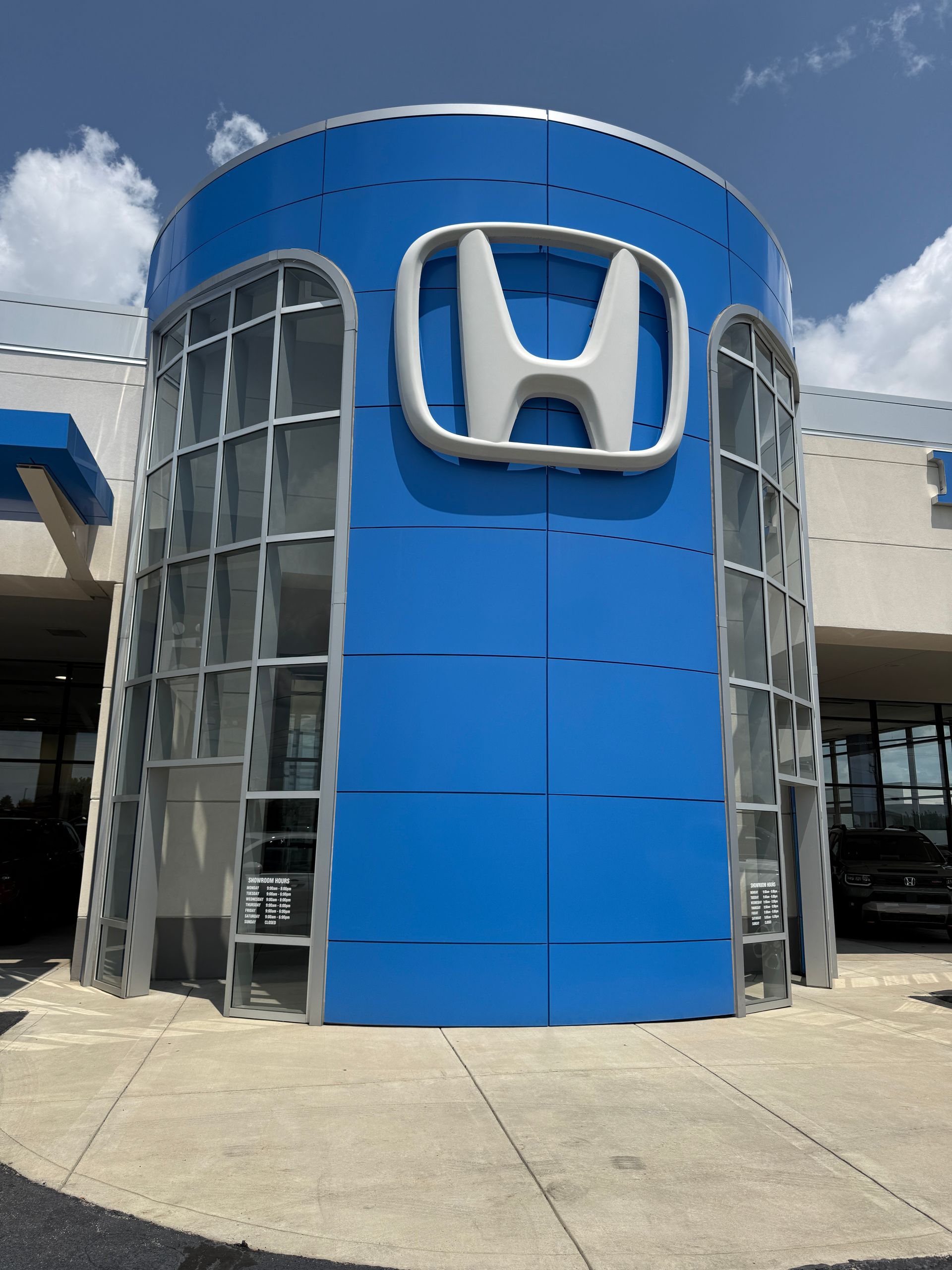 Honda dealership entrance with a large blue cylindrical facade and silver Honda logo.
