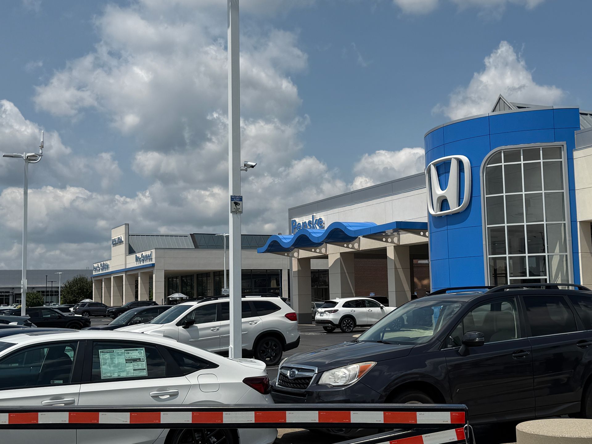 Honda dealership parking lot with several cars under a cloudy sky