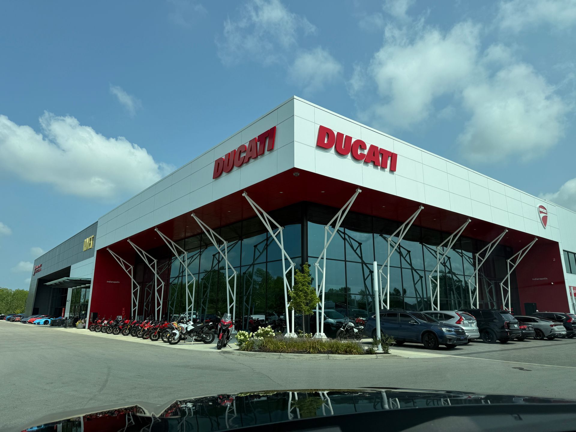 Ducati motorcycle dealership with red awning, glass facade, and parked bikes under a blue sky