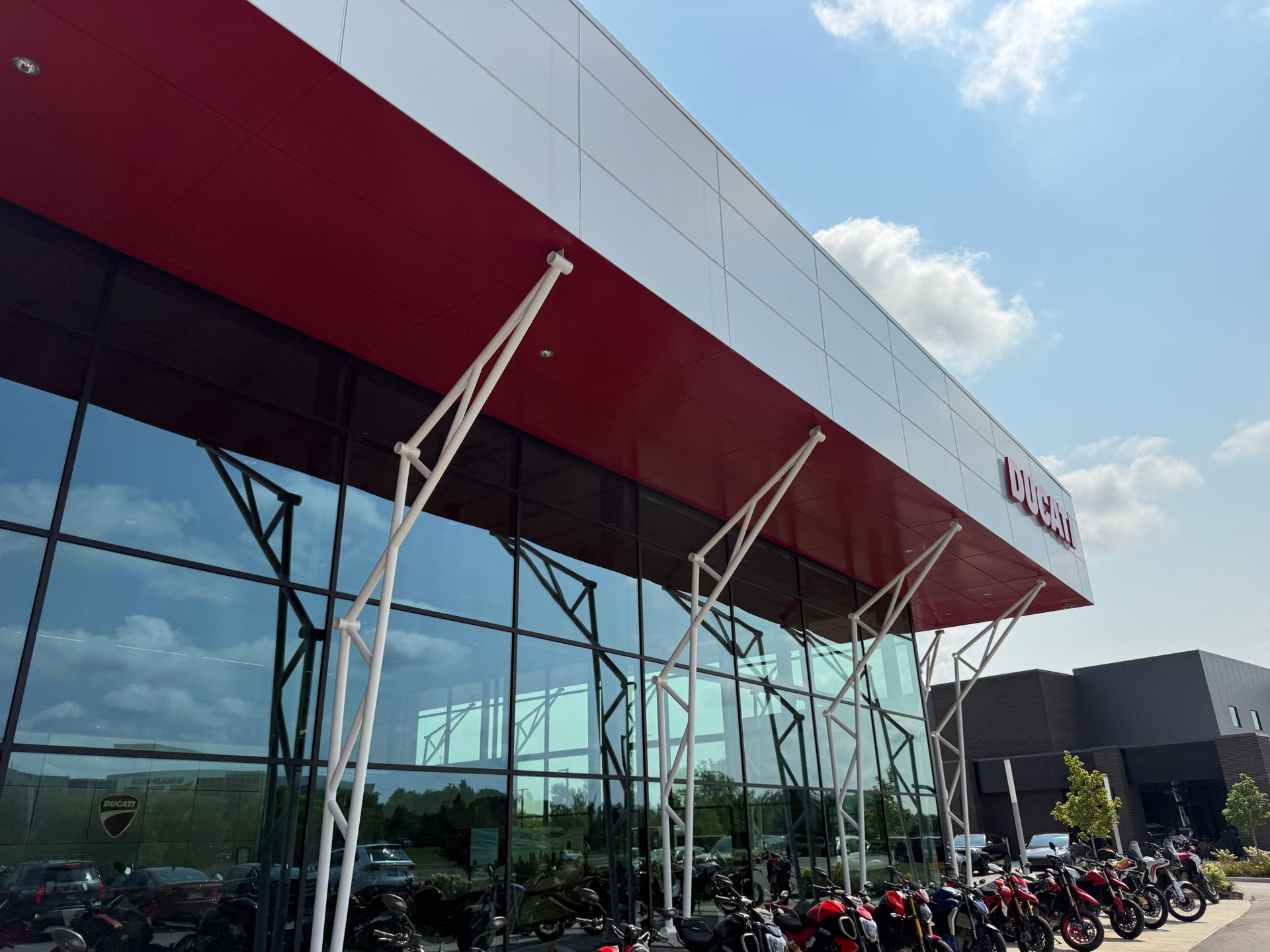 Modern glass-fronted building with red awning and parked motorcycles outside