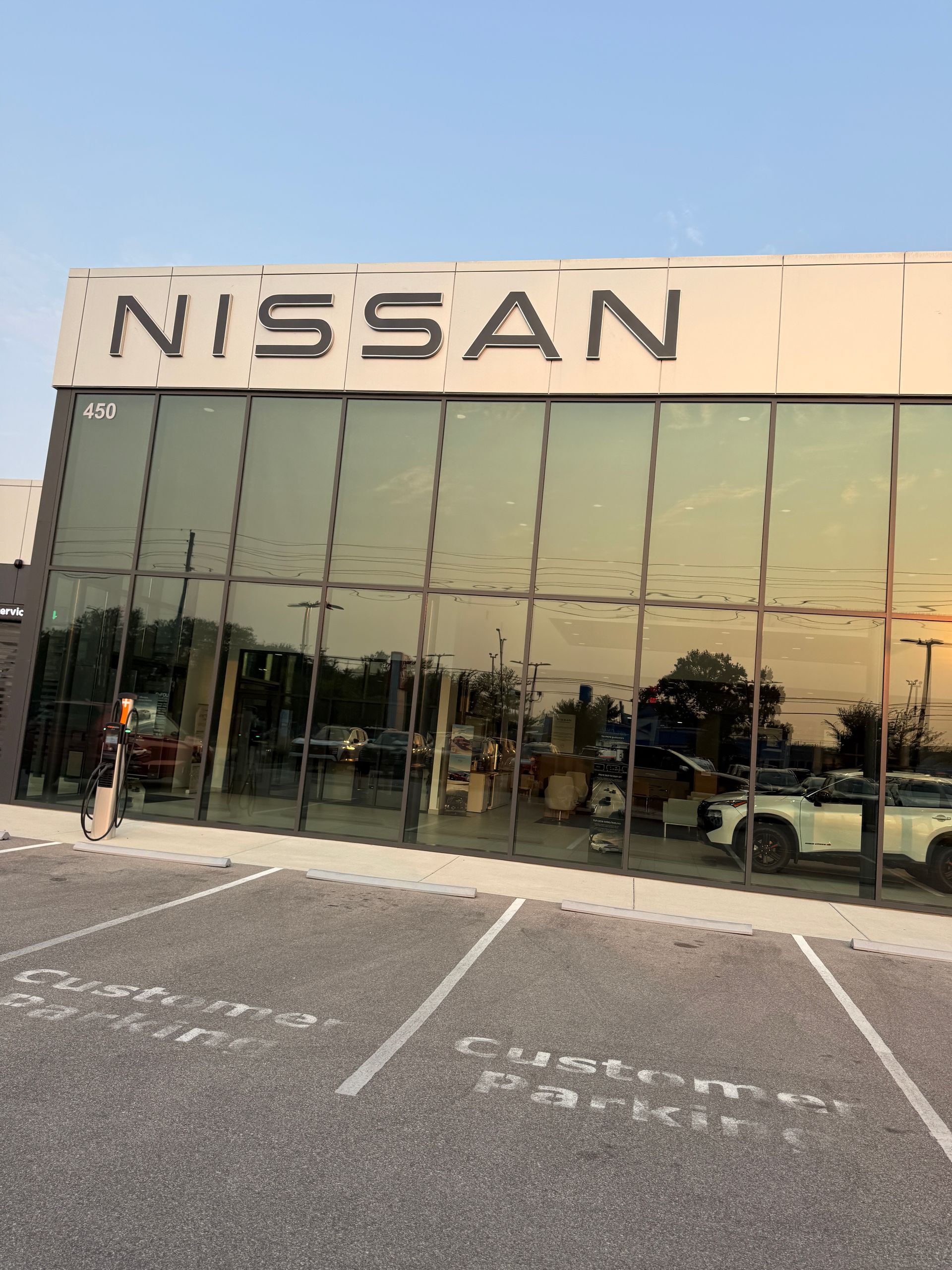 Nissan dealership exterior with glass storefront and parking spaces in front.