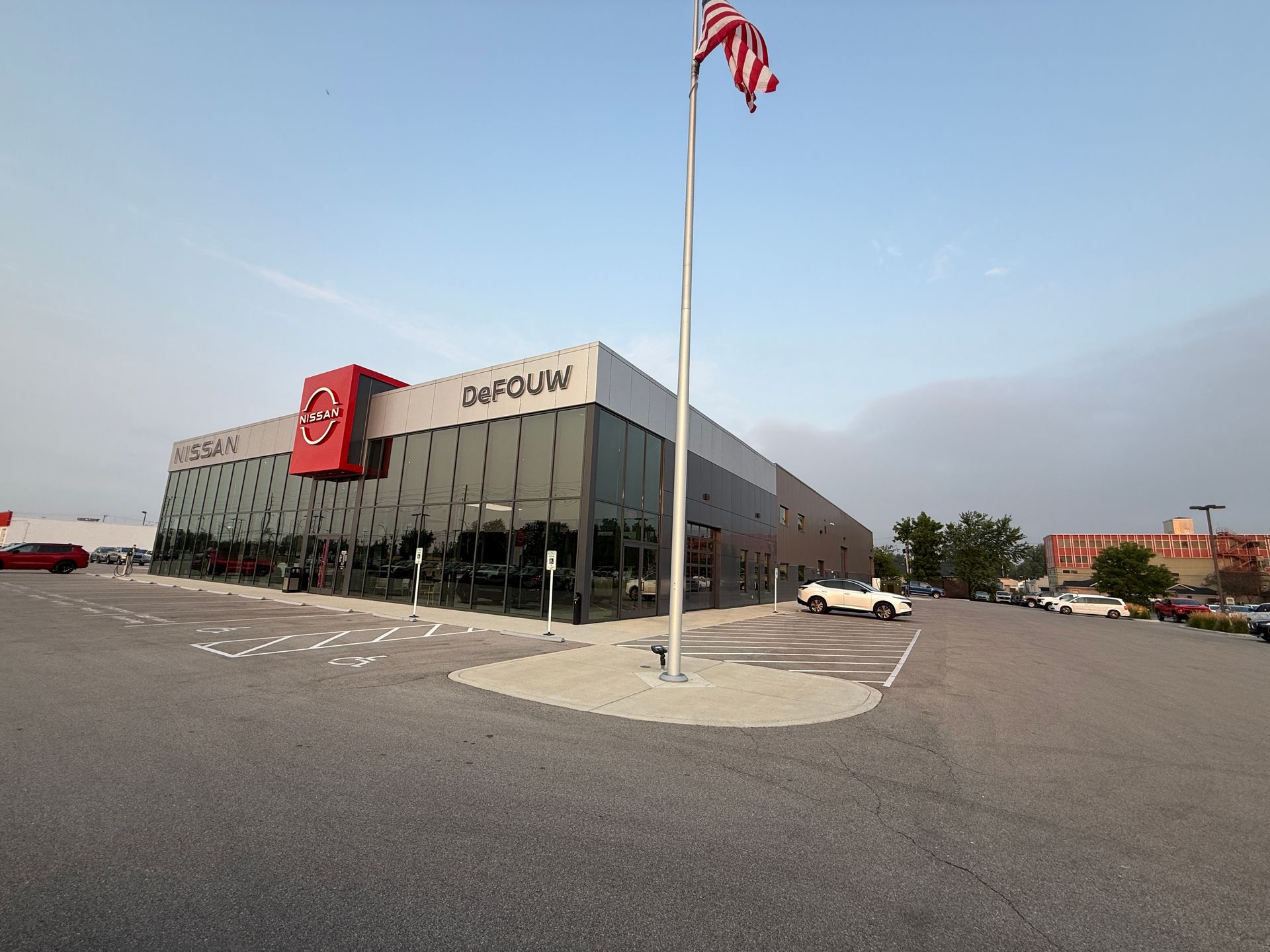 Large DICK’S Sporting Goods store with an American flag on a tall pole in a parking lot under a blue sky