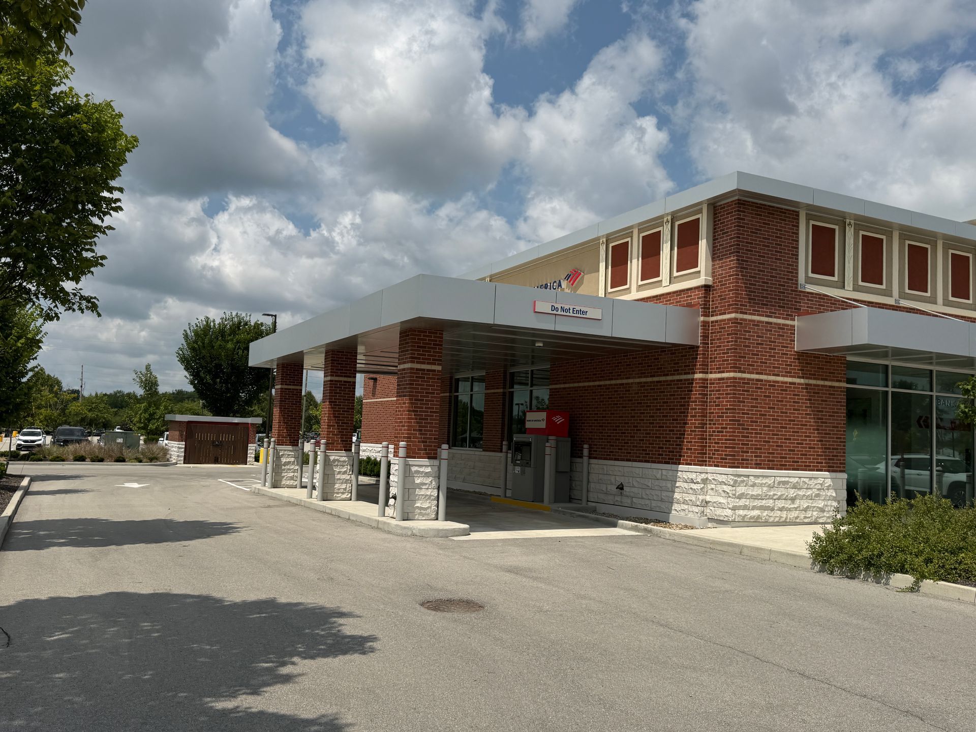 Brick building with glass entrance, white trim, and a paved parking area under cloudy skies.