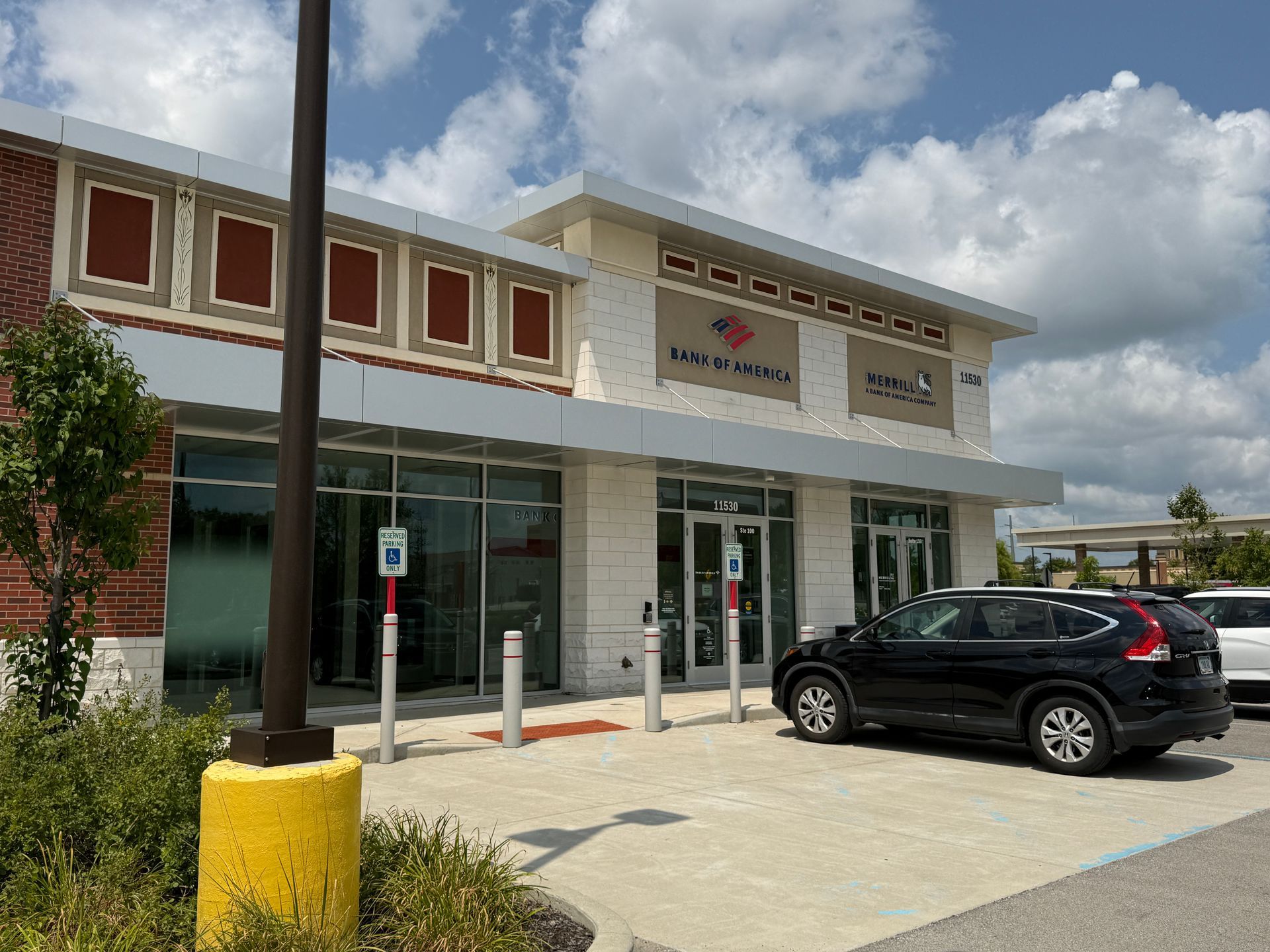 Storefront with glass windows, a black SUV parked outside, and a cloudy sky overhead.