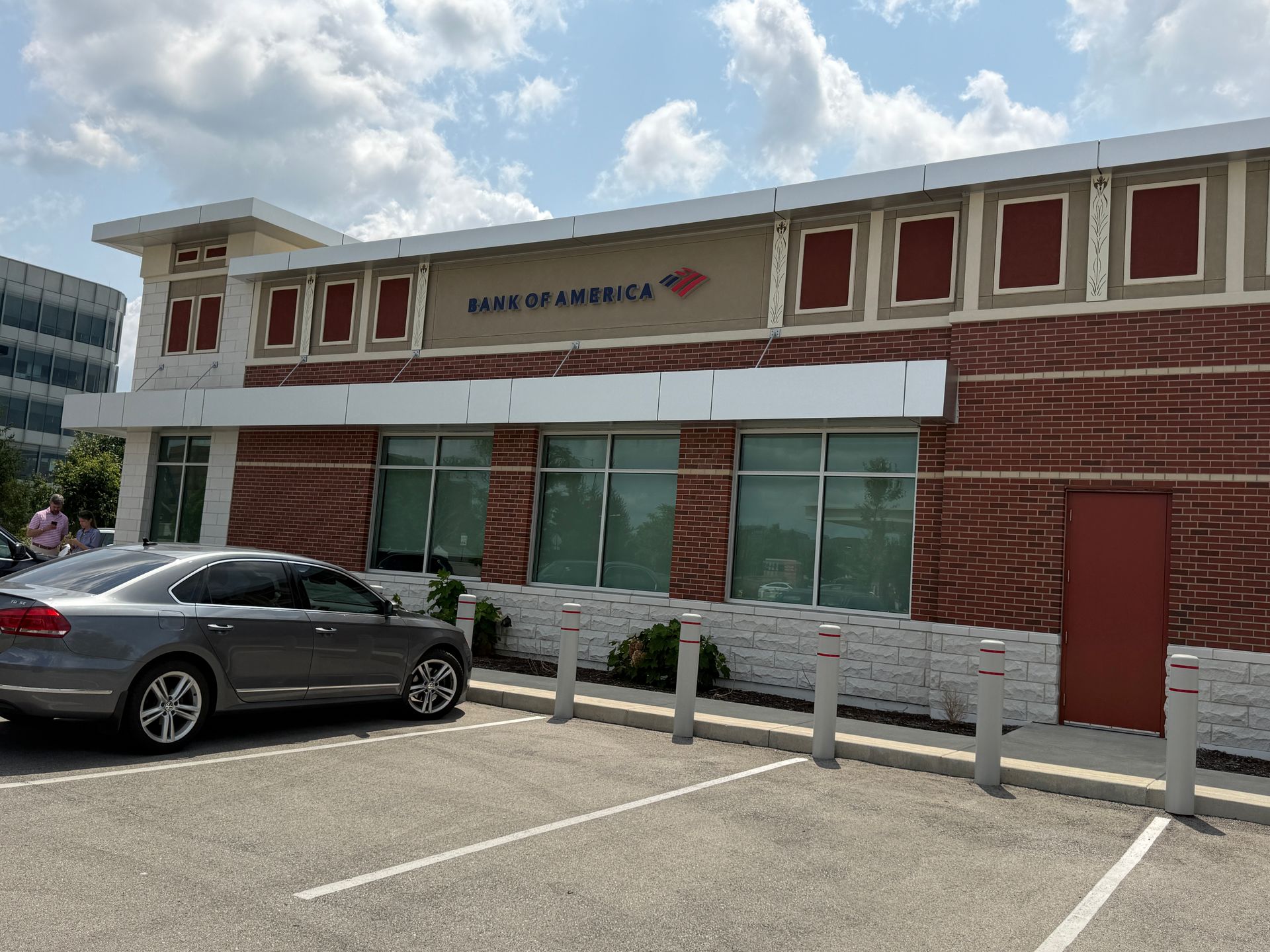 Strip-mall storefront with parked sedan and blue sky overhead