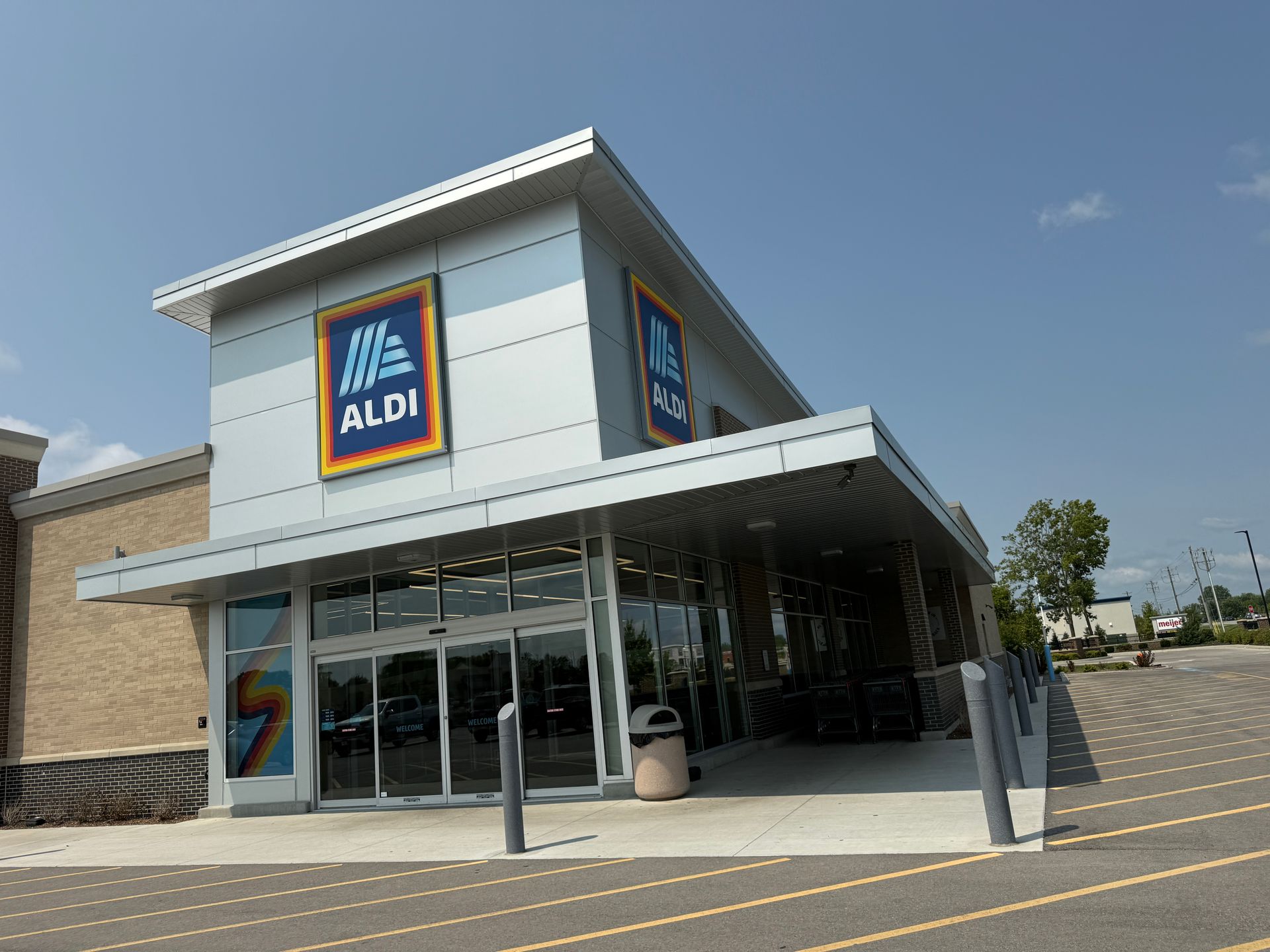 ALDI grocery store exterior with glass entrance and blue sign on a sunny day