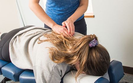 A woman is laying on a table getting a massage from a doctor.