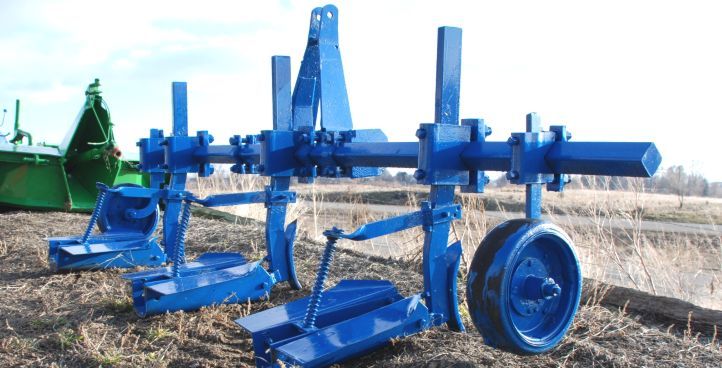 A blue machine is sitting in the middle of a field.