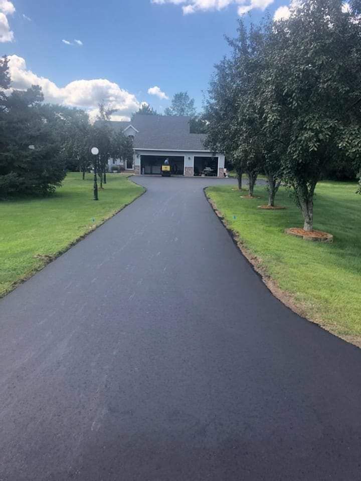 A driveway leading to a house with a car parked in the garage.