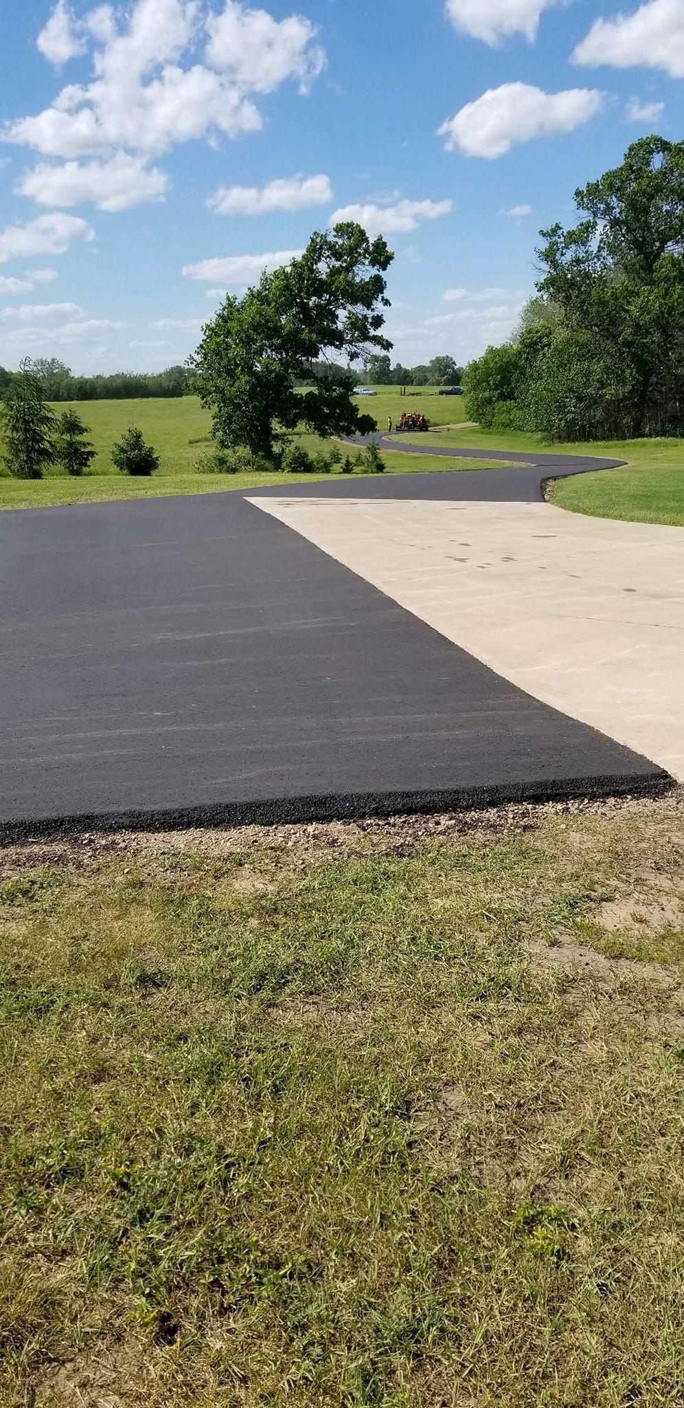 A black and white driveway with a grassy field in the background.
