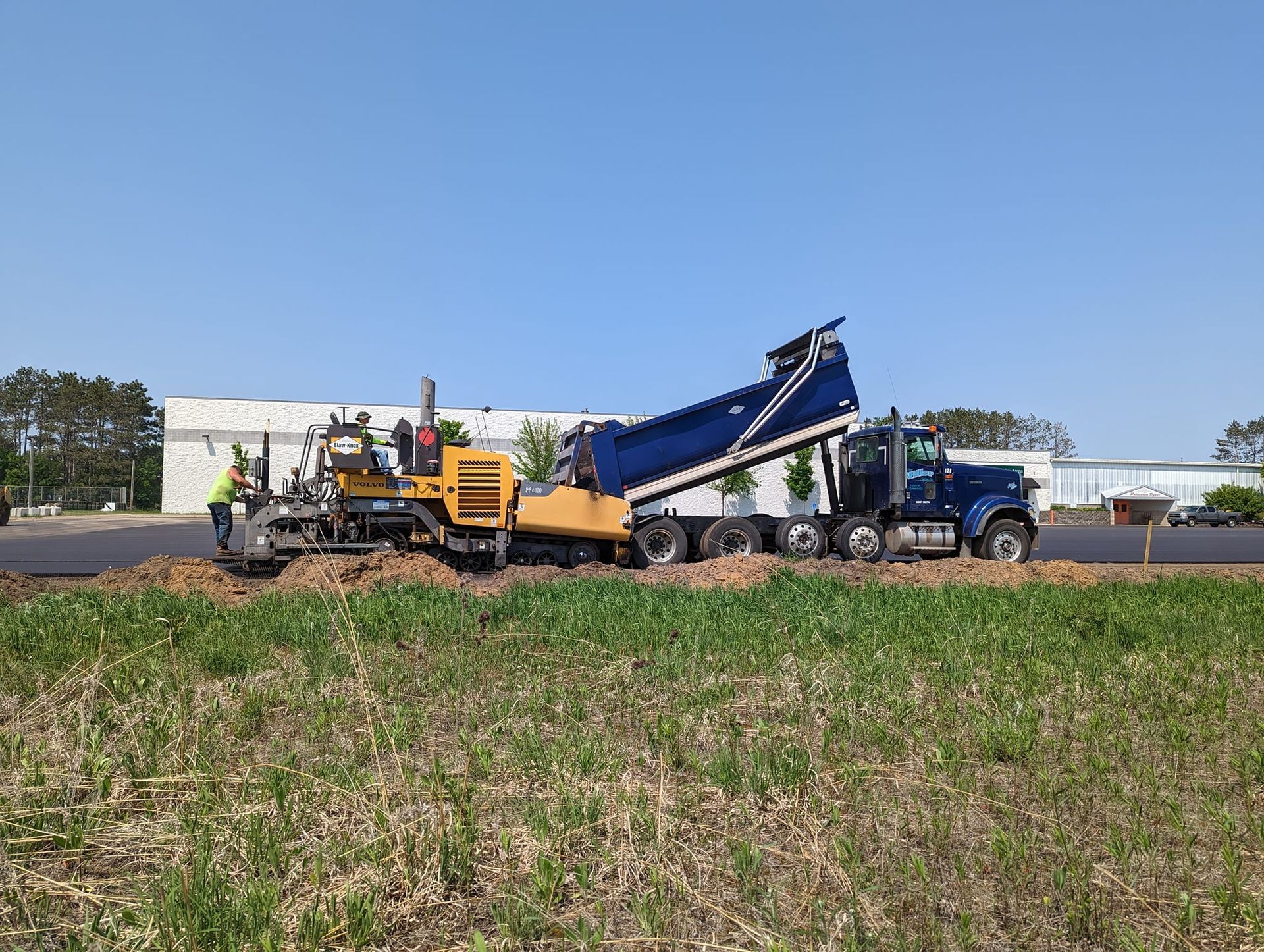 A dump truck is driving down a road next to a field.