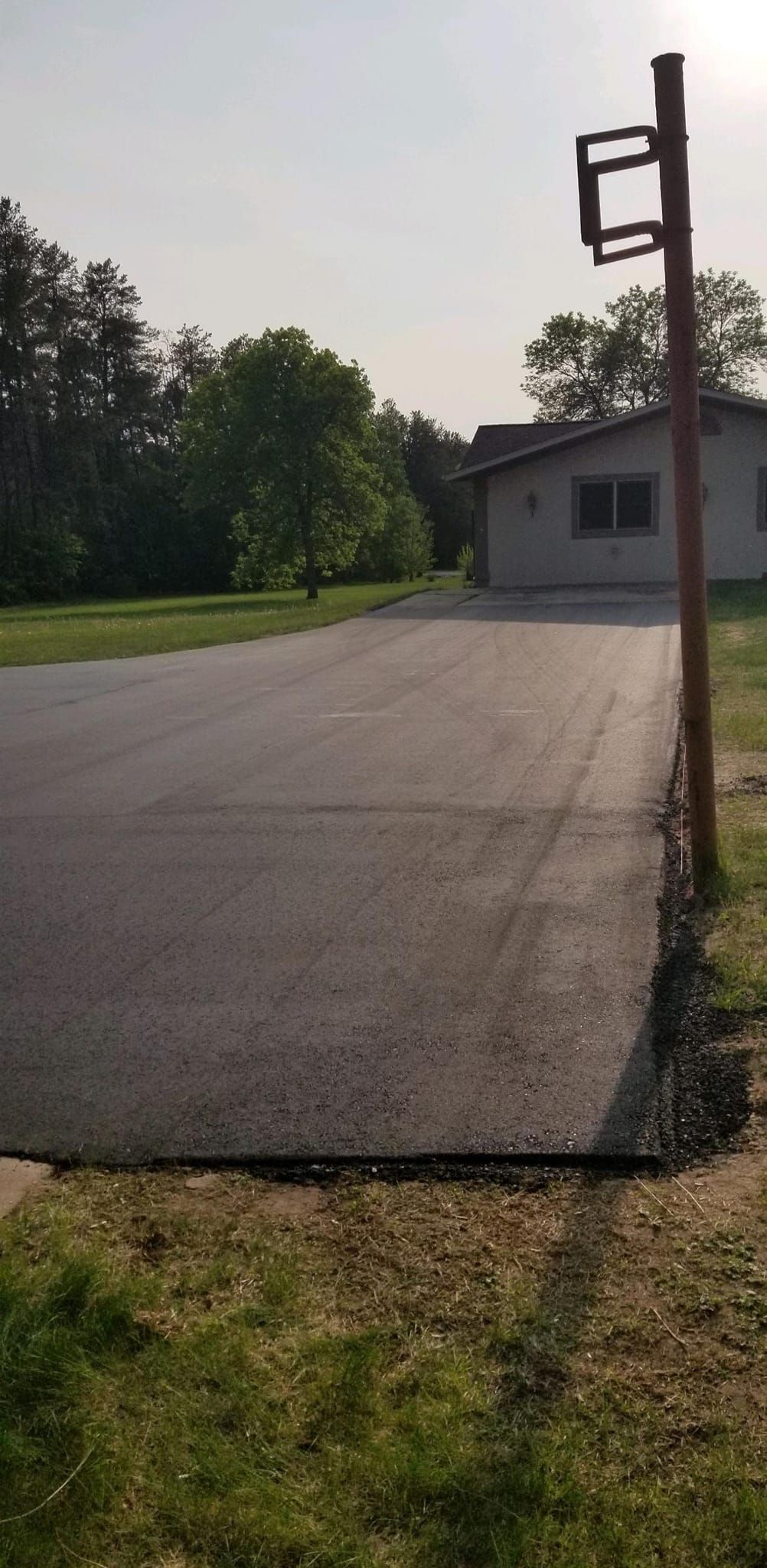 There is a basketball hoop in the middle of a driveway.