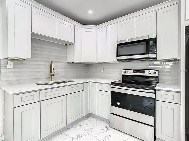 A kitchen with white cabinets and stainless steel appliances.