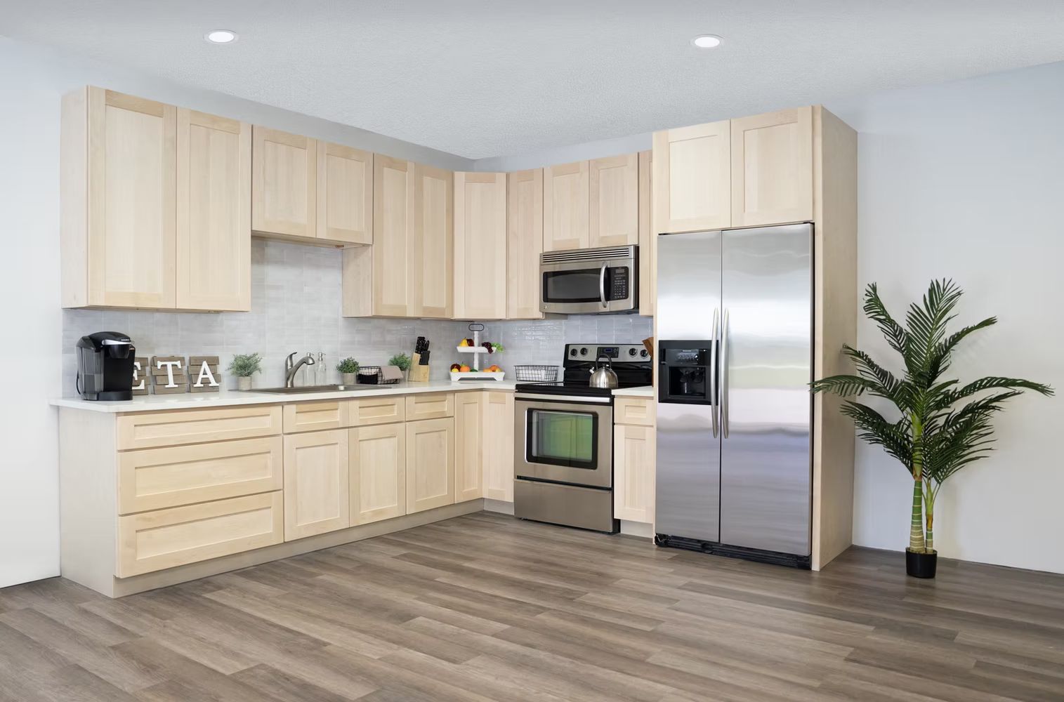 A kitchen with white cabinets, stainless steel appliances, a sink, and a desk.