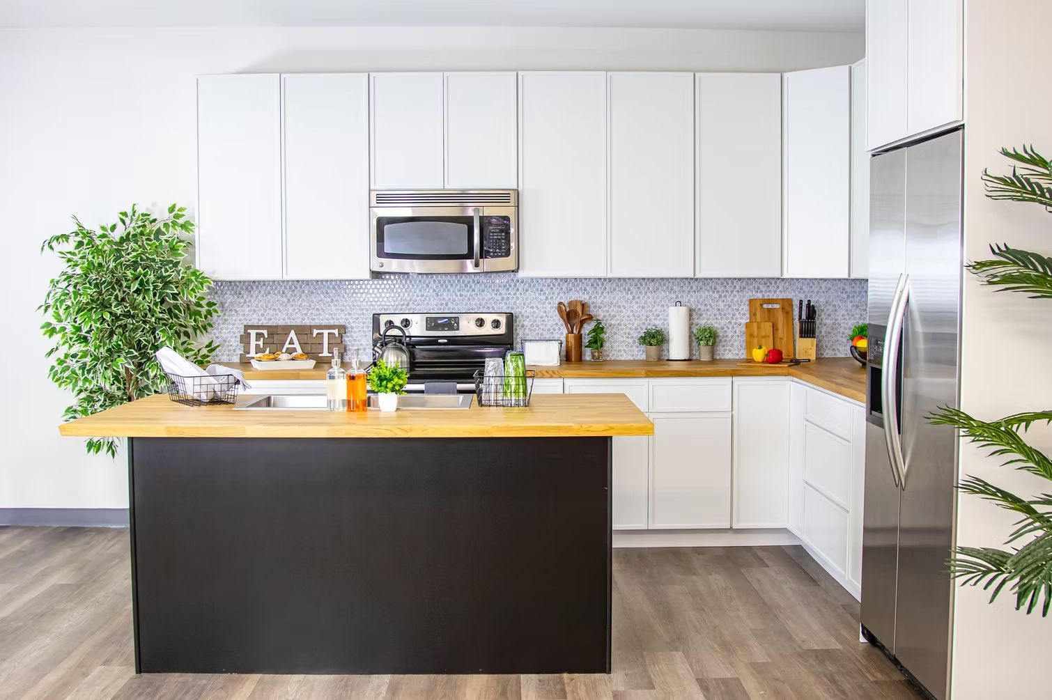 A kitchen with white cabinets, stainless steel appliances, and a black island.