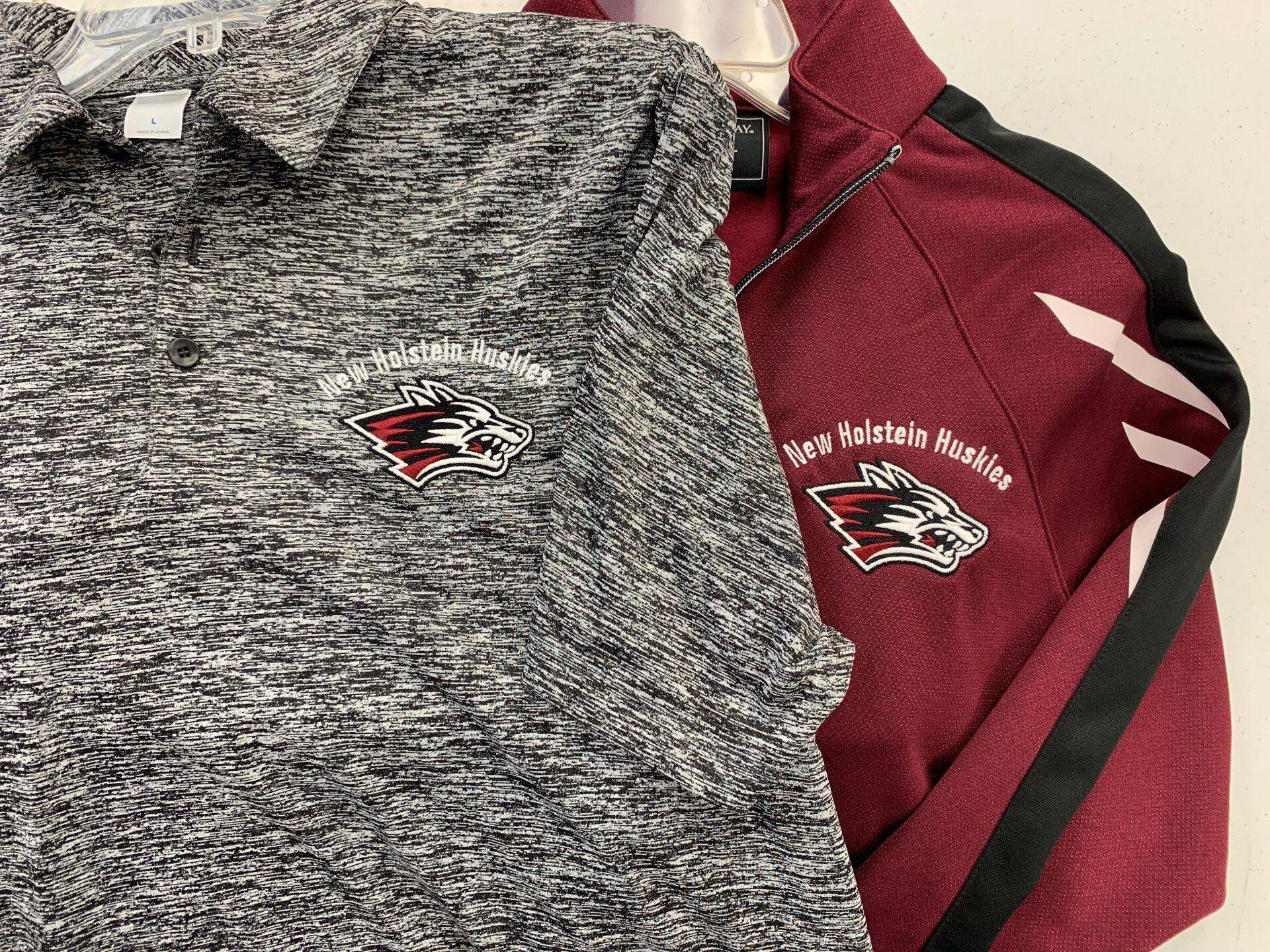 A gray shirt and a maroon jacket are sitting next to each other on a hanger.