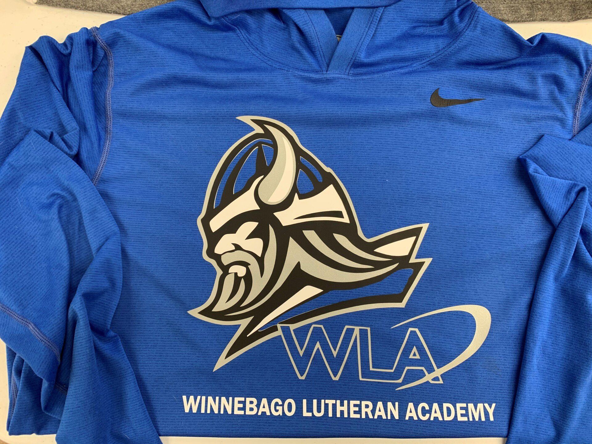 A blue shirt with a viking on it that says winnebago lutheran academy