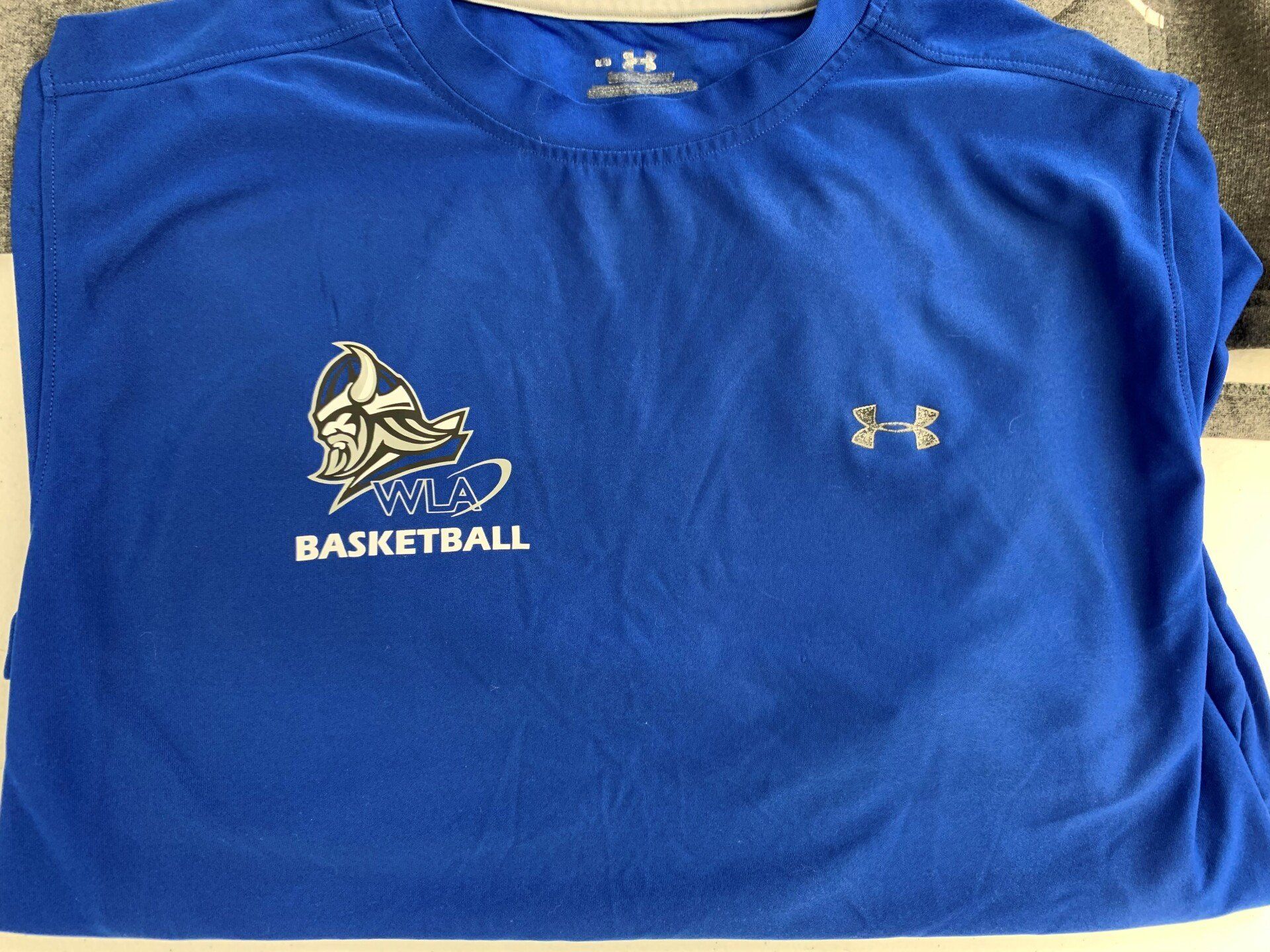 A blue under armour shirt with a basketball logo on it
