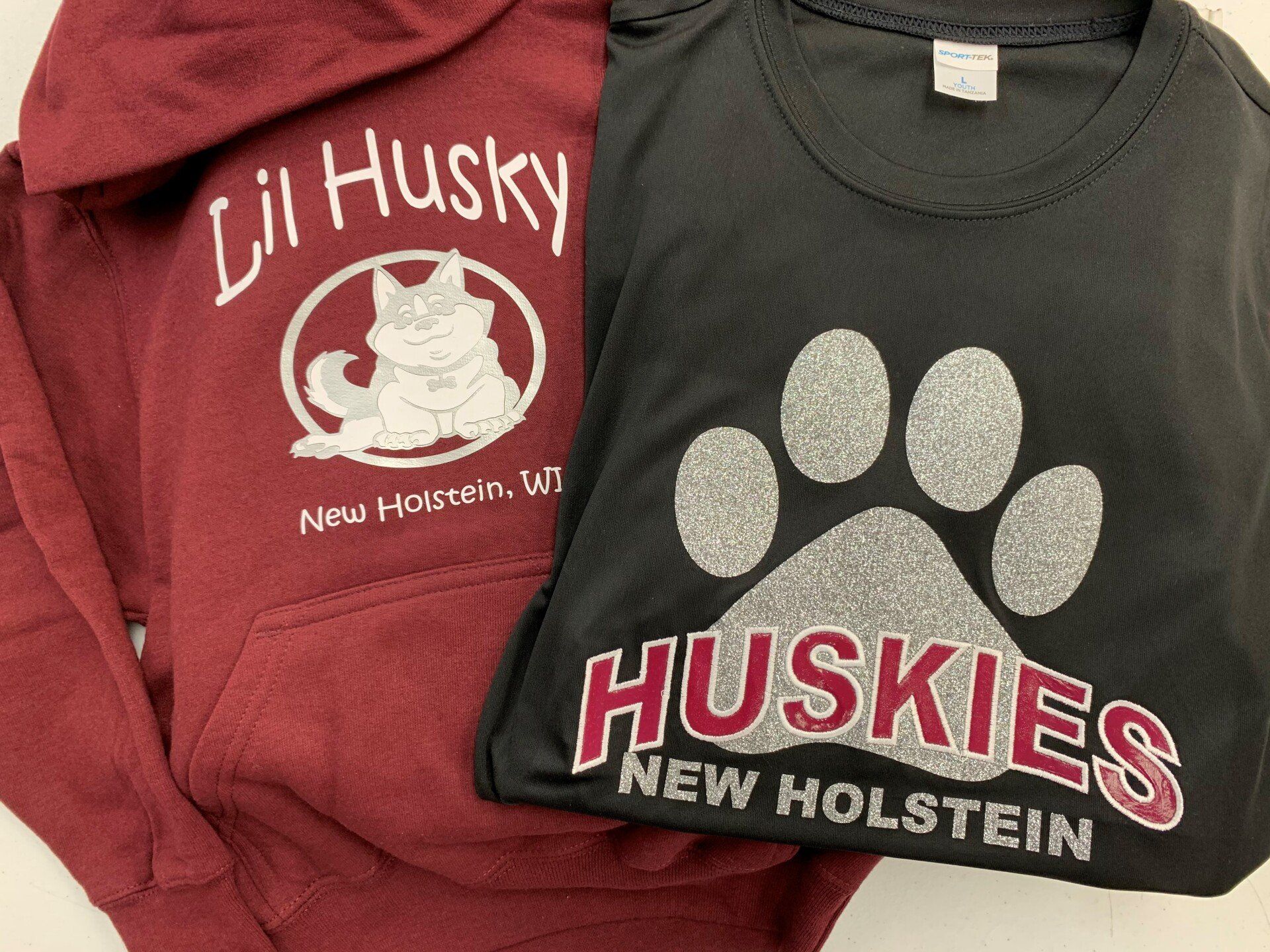 A red lil husky hoodie and a black huskies new holstein t-shirt