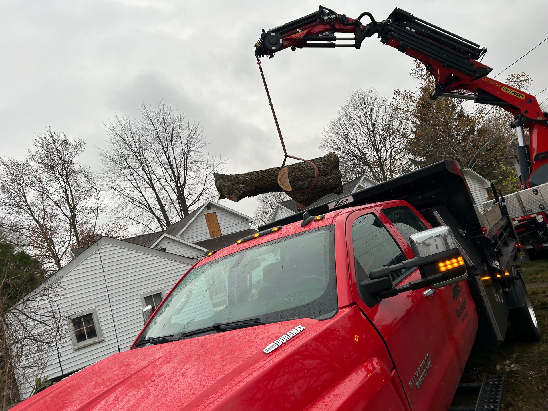 A red truck is being lifted by a crane.