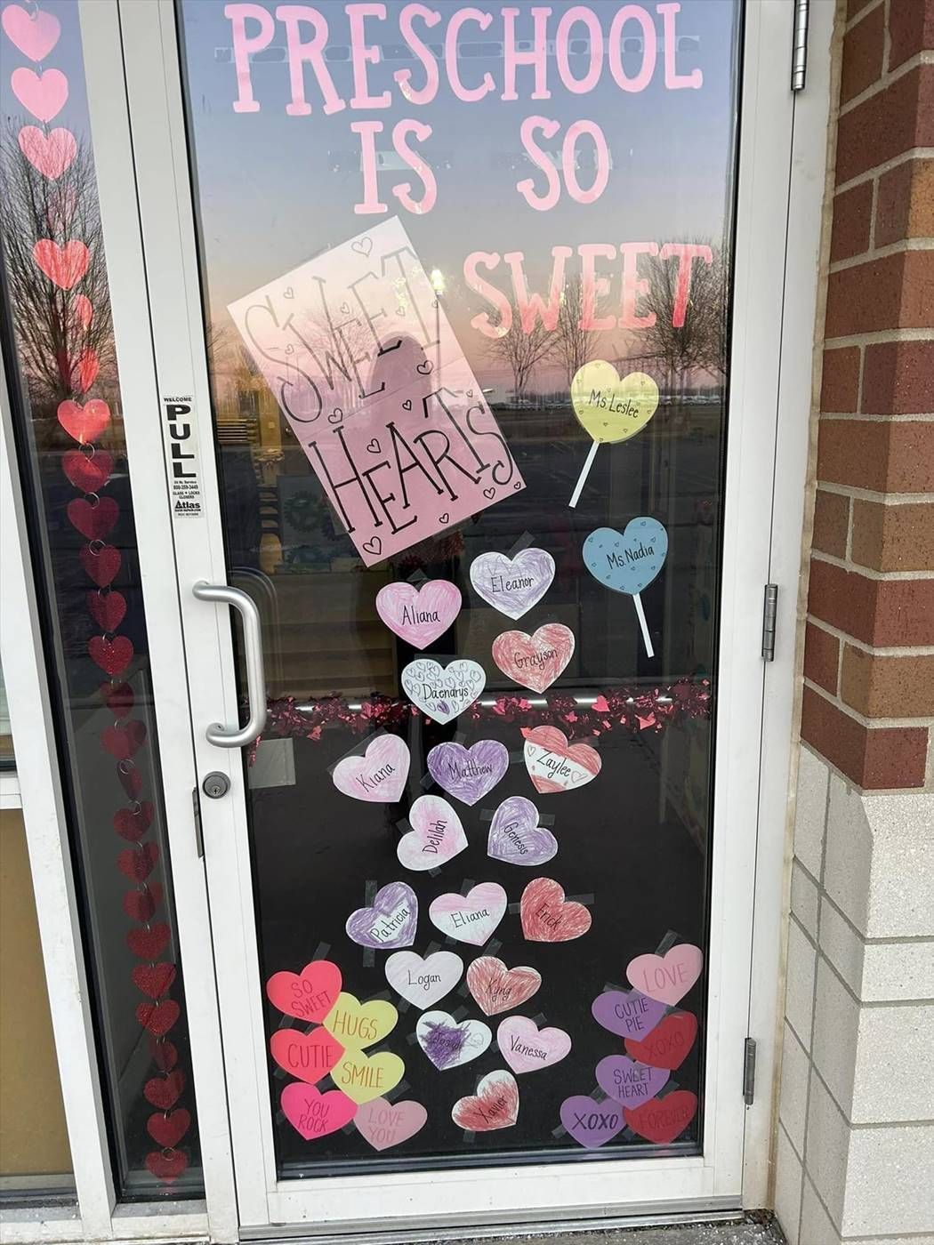 A glass door decorated with pink heart cutouts and a sign reading 