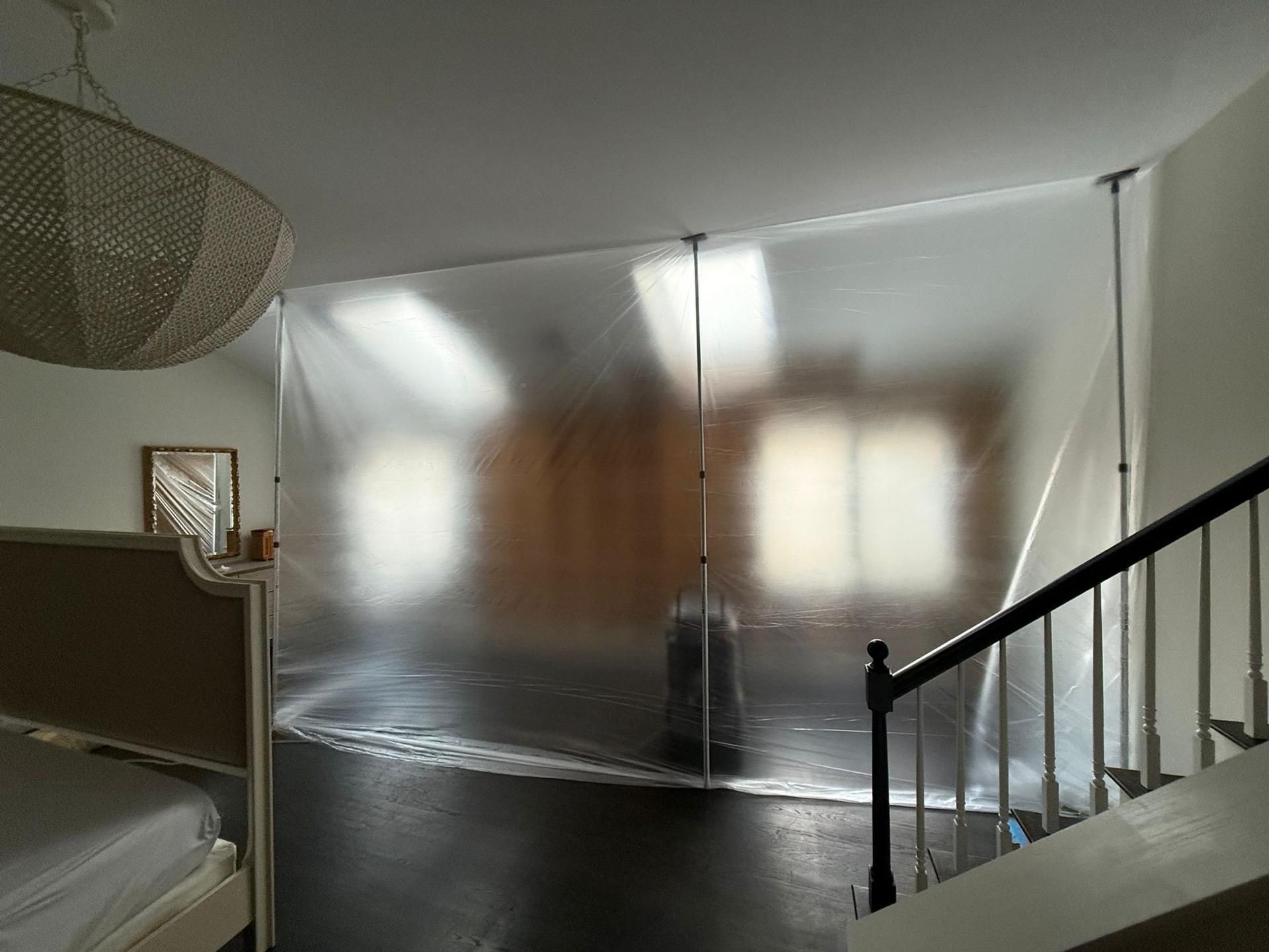 Bedroom with a bed, frosted wall panels, and a staircase railing in the foreground.