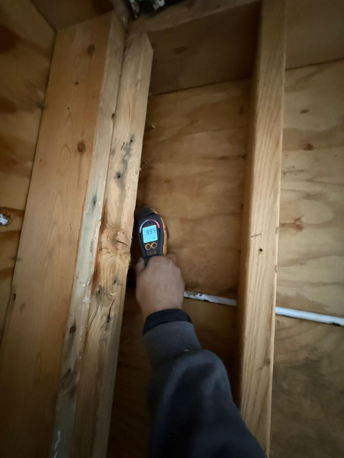 Hand holding a thermal camera inside an unfinished wooden wall frame, checking insulation.