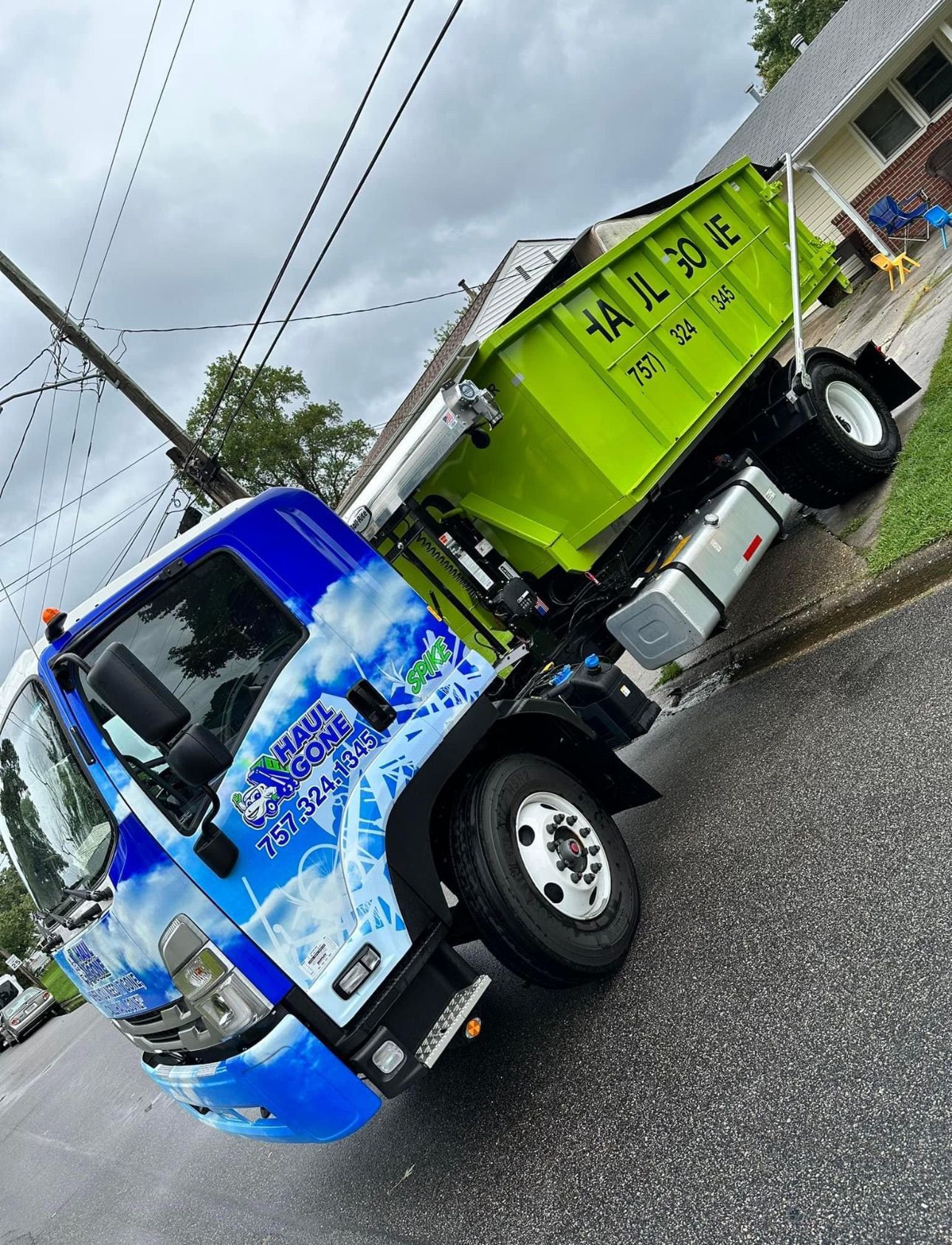 a blue and green dump truck is parked on the side of the road