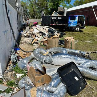 a dumpster is sitting in the grass next to a pile of trash