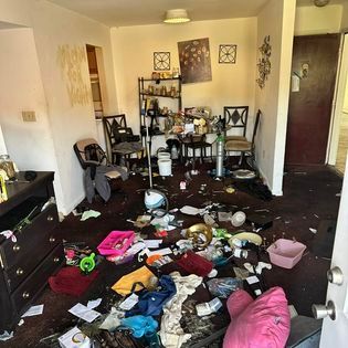 a messy living room with a table and chairs