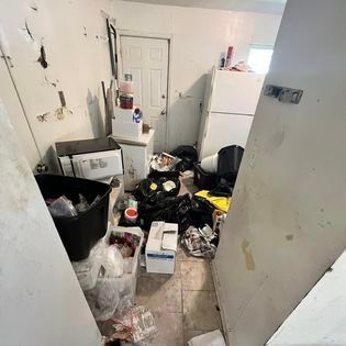 a room with a lot of trash in it and a refrigerator