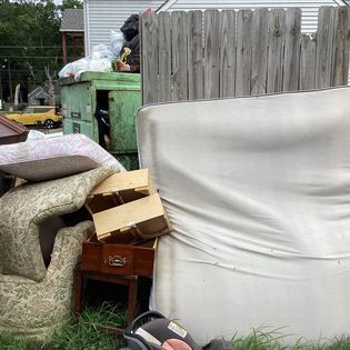 a pile of junk is sitting in the grass next to a dumpster
