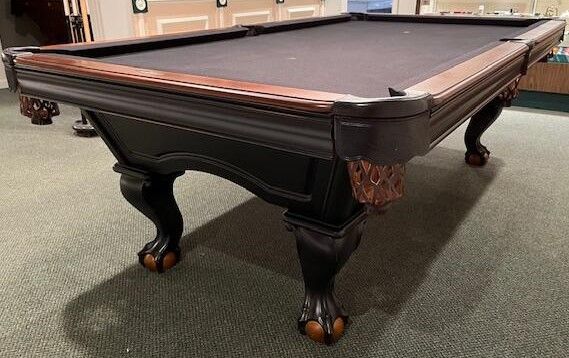 A pool table is sitting on a carpeted floor in a room.